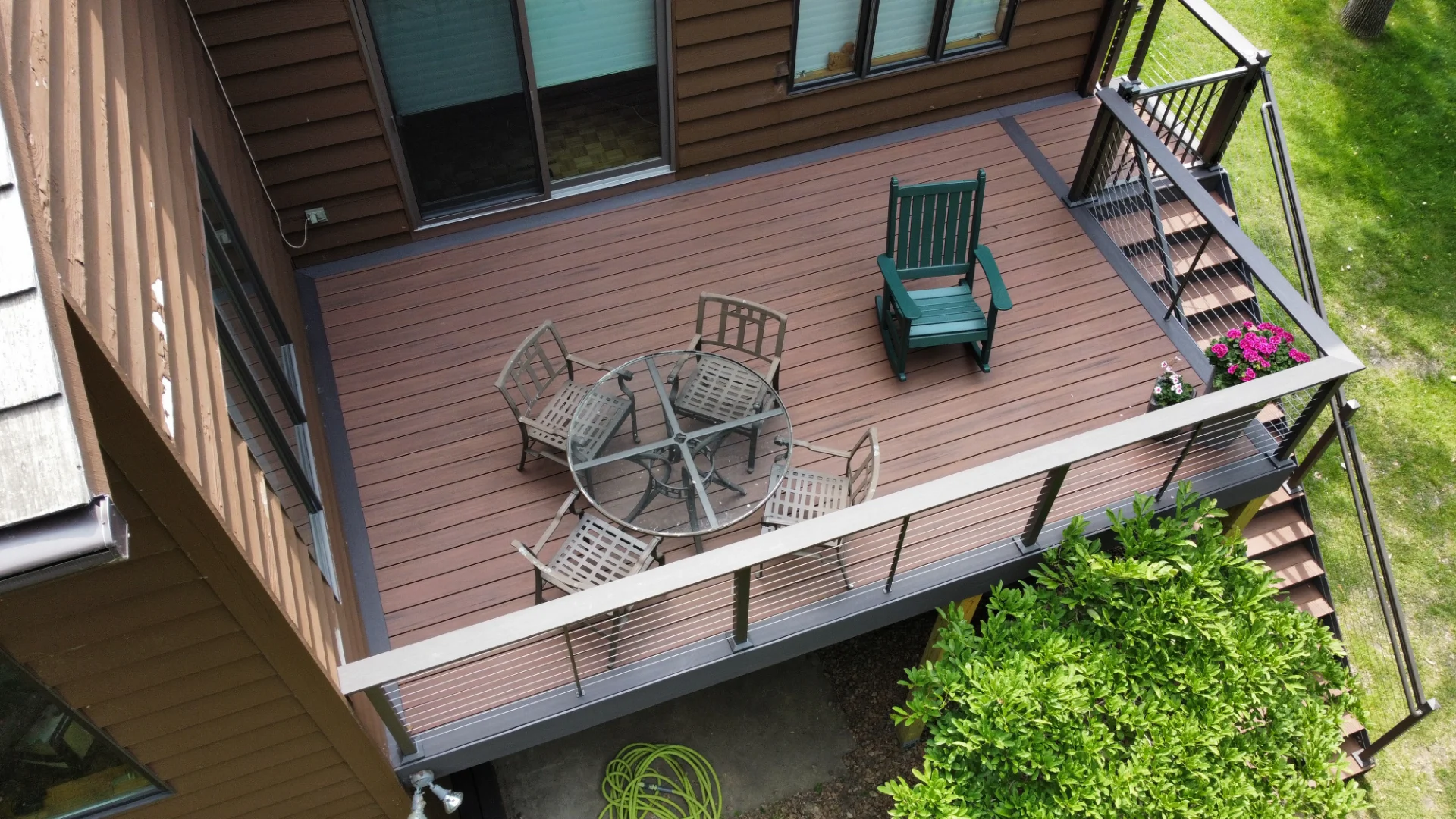 Deck with Metal Cable Railings and Glass Table with Chairs and Potted Flowers